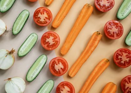 Top view of fresh sliced vegetables including carrots, cucumbers, onions, and tomatoes in a flat lay design.