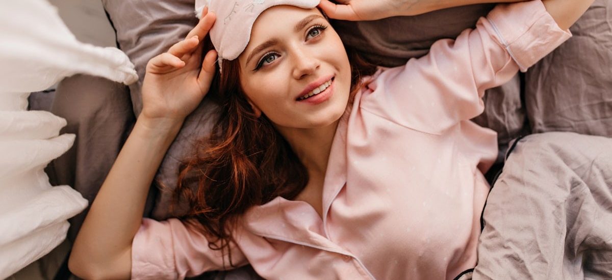 a woman laying on top of a bed next to a pillow