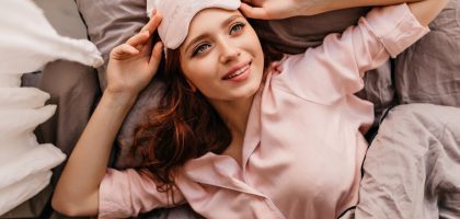 a woman laying on top of a bed next to a pillow