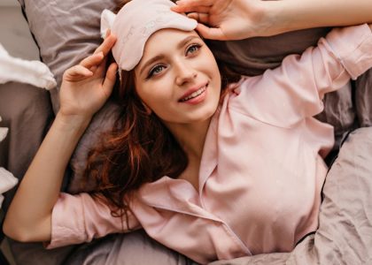 a woman laying on top of a bed next to a pillow